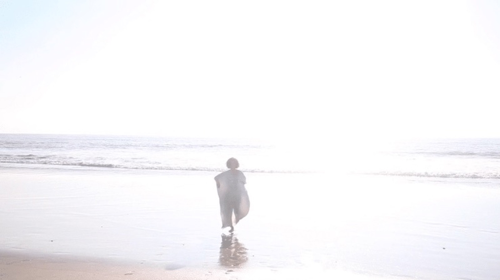 A lone figure walking toward a luminous sea, from At the Edge of the Sea