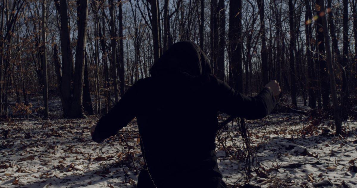 A figure untangles a rope in reverse in snowy woods — Disturbance