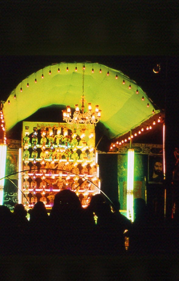An illuminated arch of coloured lights frames a shrine in a darkened room — Sacred Spaces