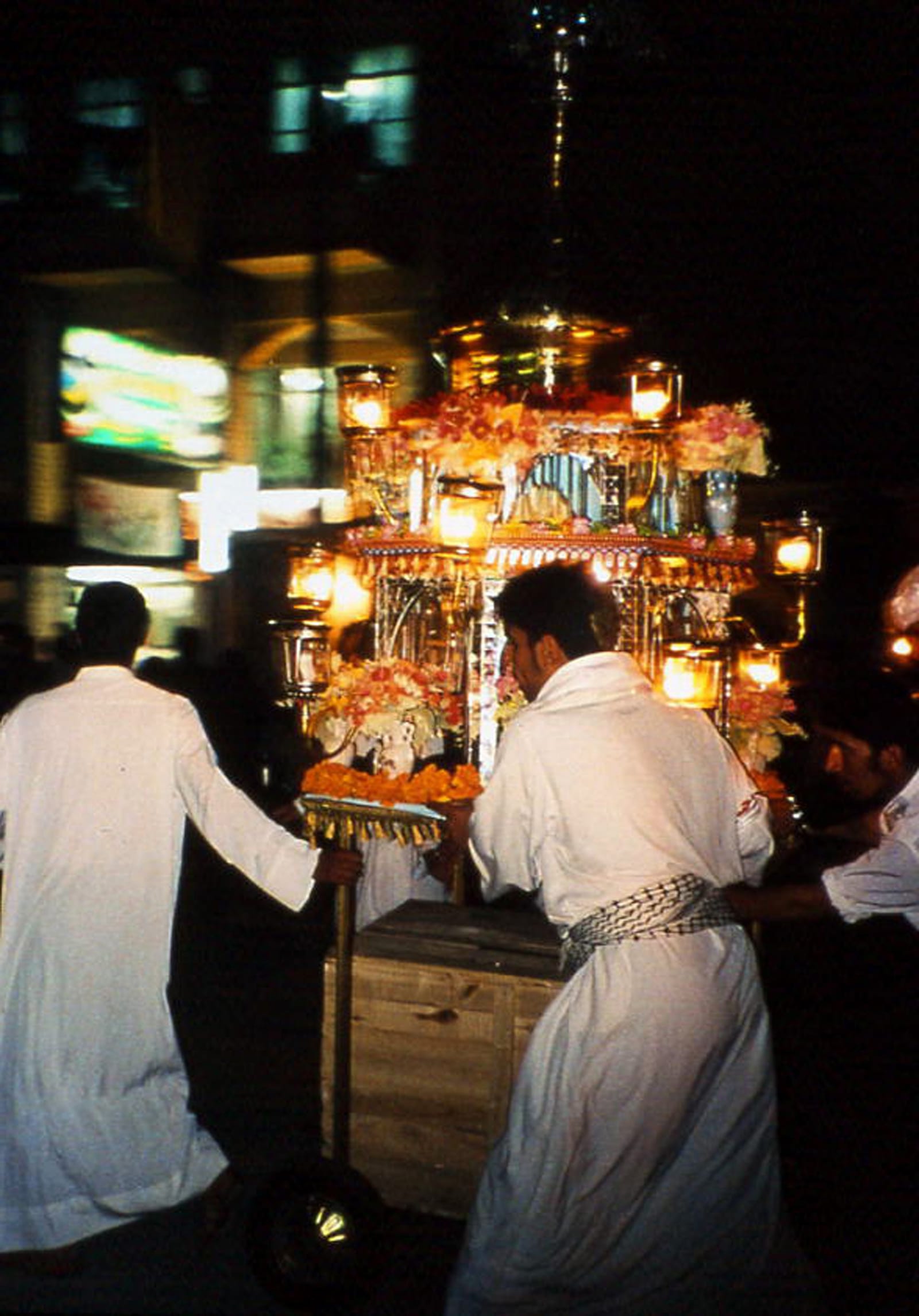 Men push a laden cart through a procession of lights — Sacred Spaces