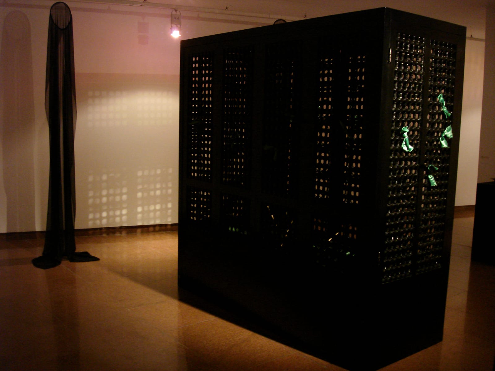 A dark monolithic structure stands in a second gallery room — Sacred Spaces